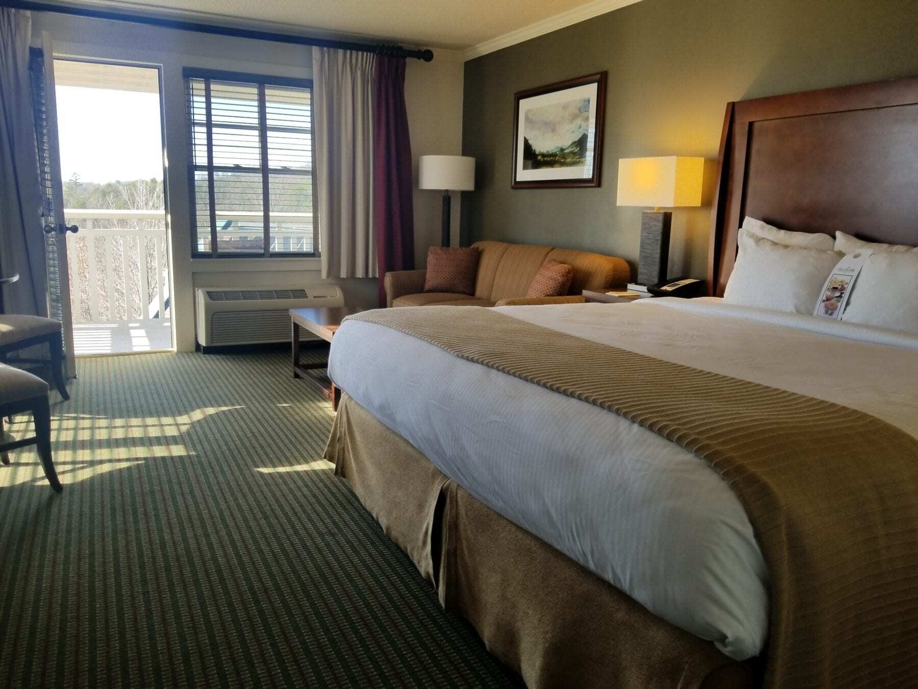 "Spacious hotel room at Brasstown Valley Resort in Young Harris, Georgia, with a comfortable king size bed positioned to offer a stunning view of the Blue Ridge Mountains from the private patio."
