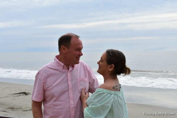 reisblogger Kathy Brown kijkt naar haar geweldige man Steve terwijl hij op het strand staat. 