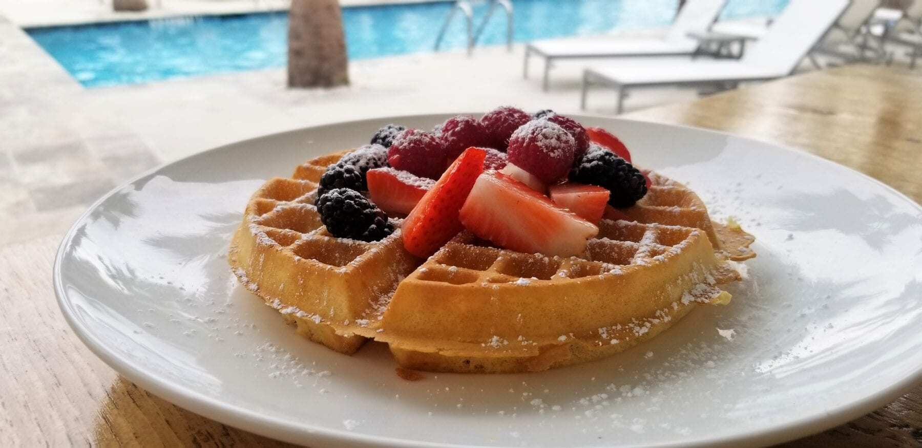 "Delicious Homemade Waffle with Fresh Strawberries and Blueberries, served by the Resort Pool on a Sunny Summer Day at Hotel Indigo, Mount Pleasant, South Carolina."
