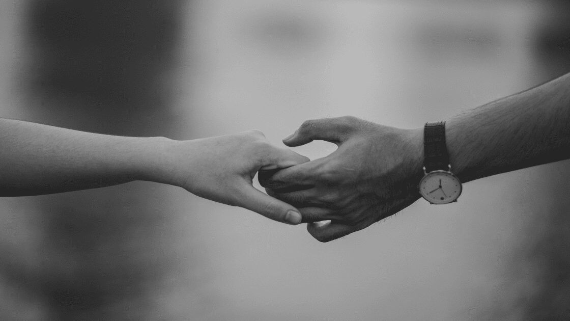 Black and white photo of two hands holding each other in a sign or love and commitment.
