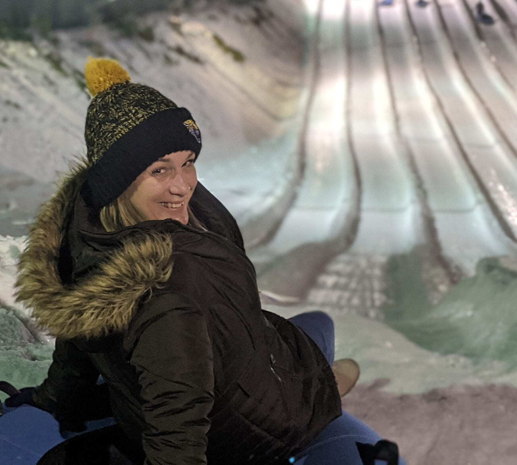 Smiling girl riding a snow tube down a snow covered mountain Image: Kathy Brown Tennessee Writer
