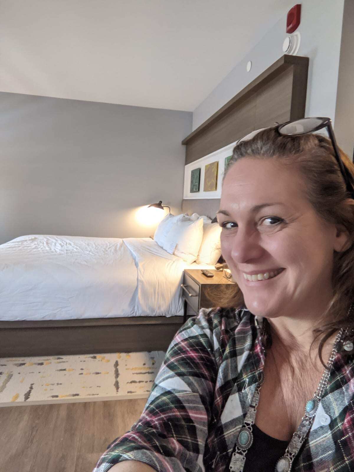 Selfie of Kathy Brown inside the Chattanooga Hotel Indigo. King size bed in background