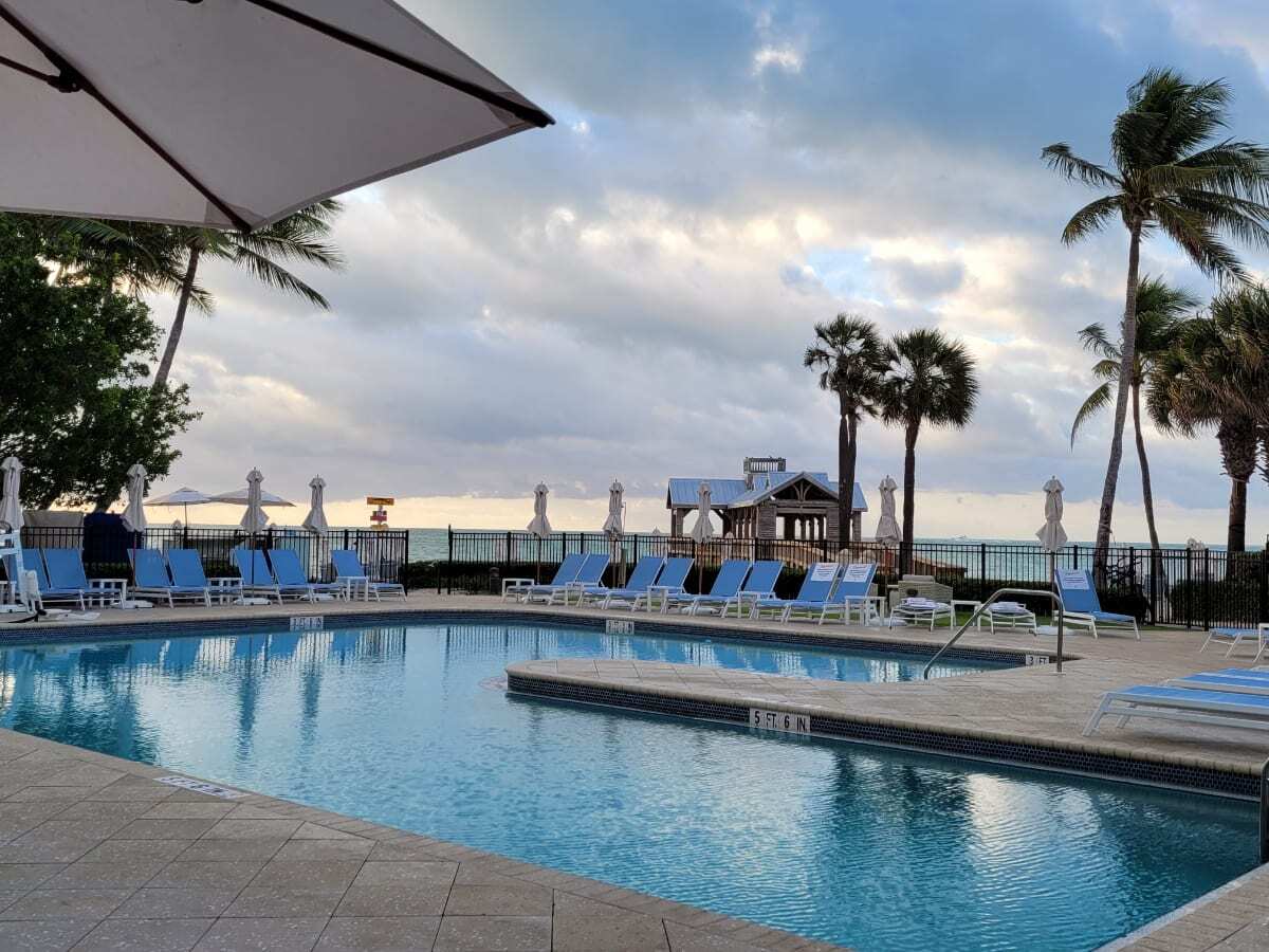 Crystal clear blue water pool and umbrella overlooking the beach and palm trees. Image: Travel Blog Finding Kathy Brown