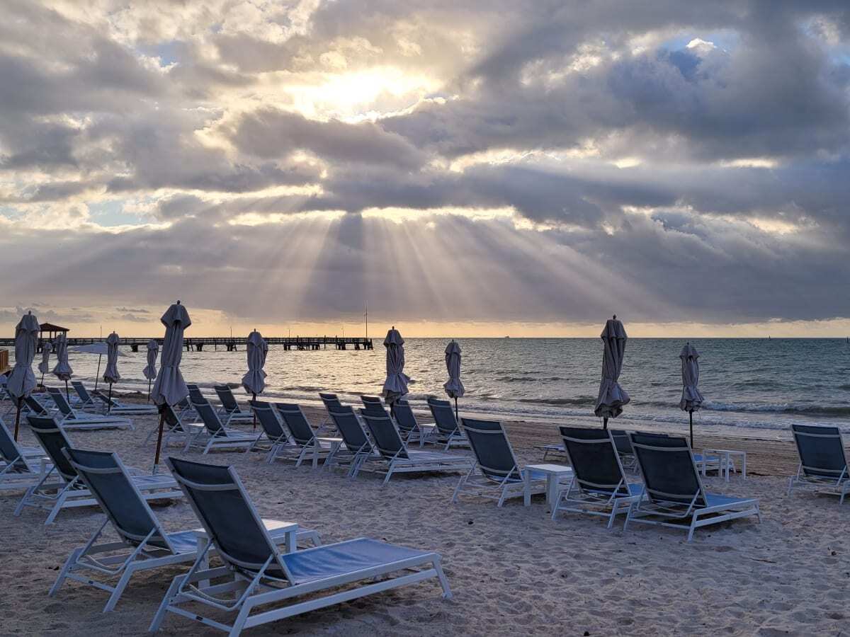 sun set on a cloudy Florida Key West Evening. Perfectly placed beach lounge chairs and umbrellas. Reach Beach Resort Key West, Florida