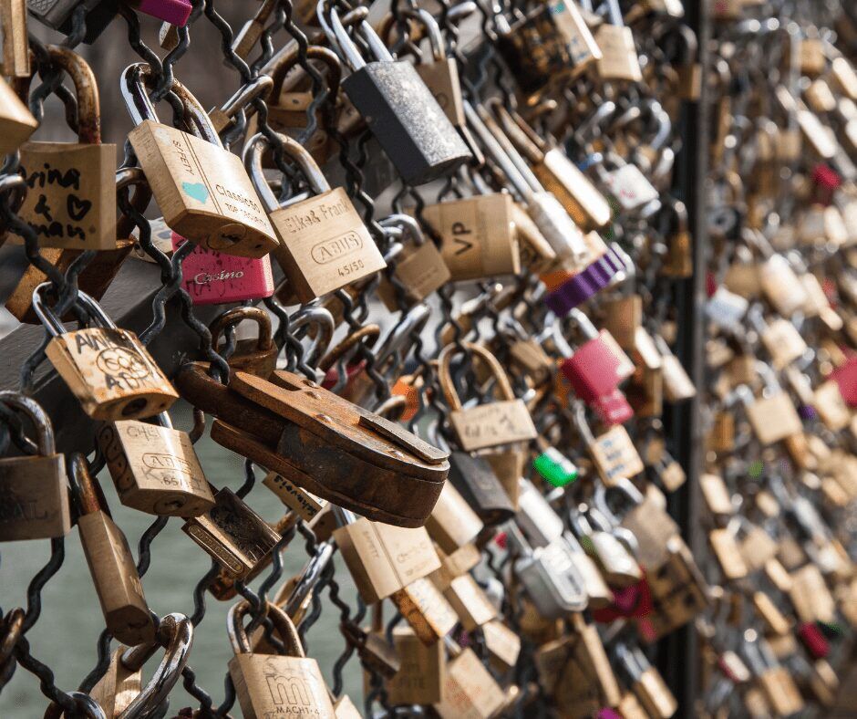 Hundreds of pad locks locked on a fence. Image: Canva