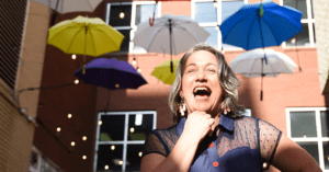Gray haired over 50 year old woman standing under umbrellas laughing in Chattanooga, TN