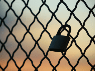 Single love lock attached to a metal railing on a bridge overpass in Boston, Massachusetts, with the city skyline in the background."