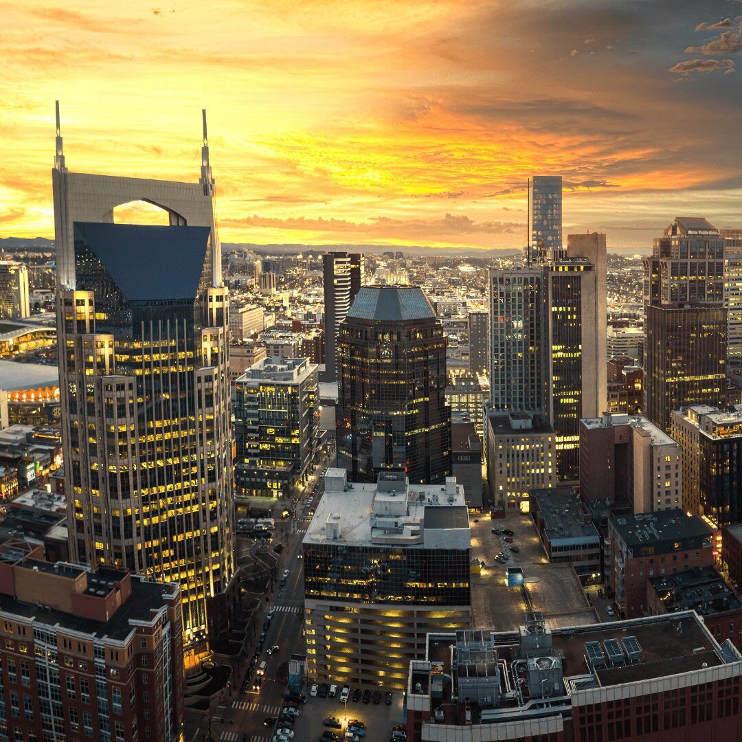 A view of the Nashville skyline at night, with brightly lit buildings and a dark sky above." "The Nashville skyline with the sun setting behind it, casting an orange glow on the buildings."