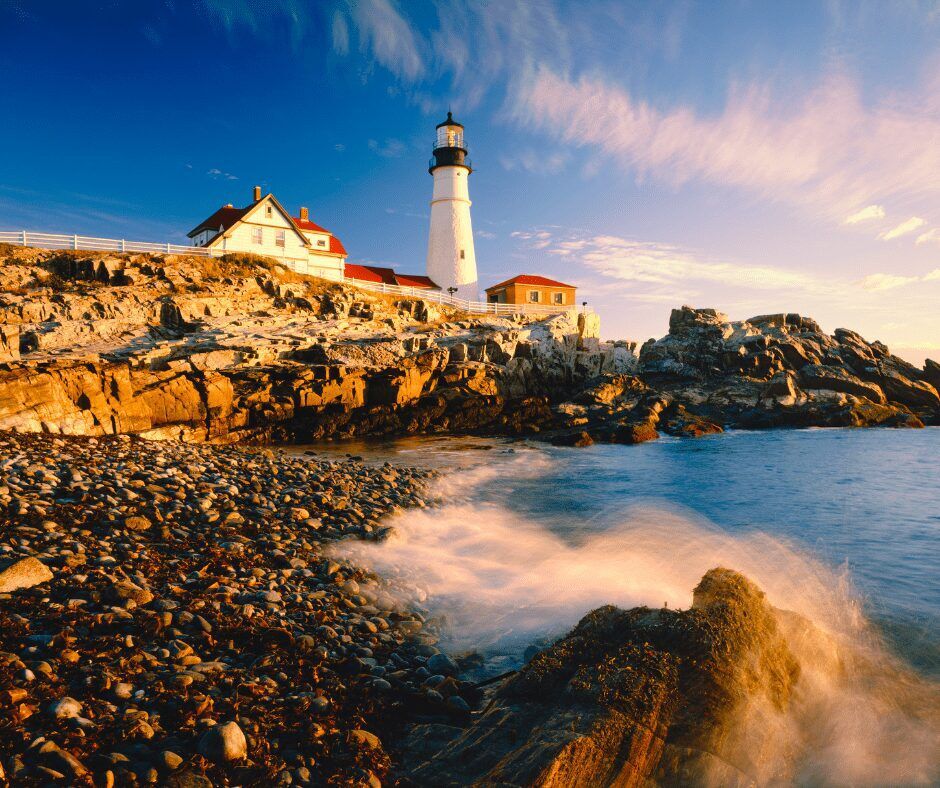 "An iconic and picturesque lighthouse situated atop a rocky cliff overlooking the ocean. The lighthouse features a white tower and red roof with the ocean and sunset sky in the background."