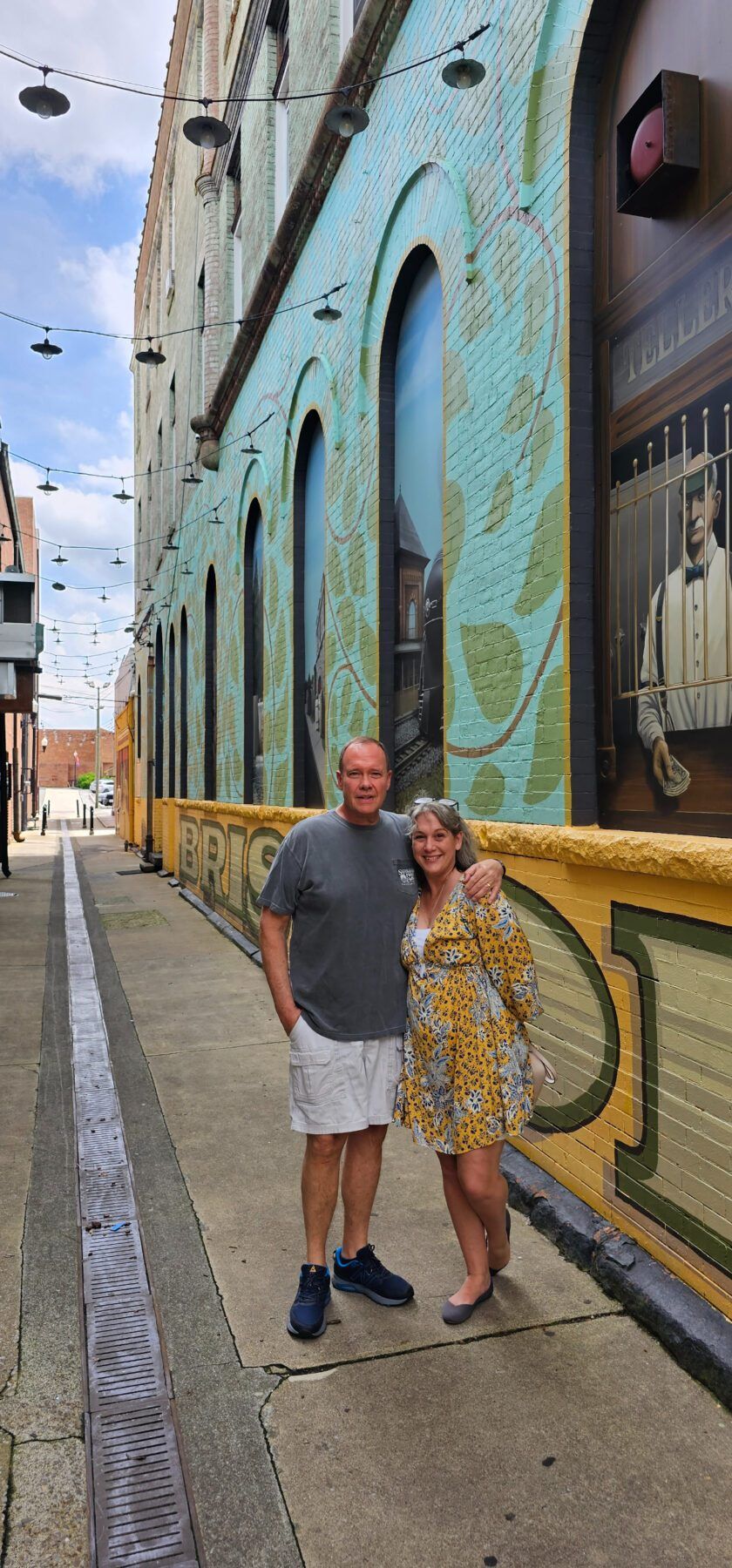 "Kathy and Steve Brown, 50 plus travel bloggers, posing in front of a vibrant downtown mural in Bristol, Virginia during their road trip."