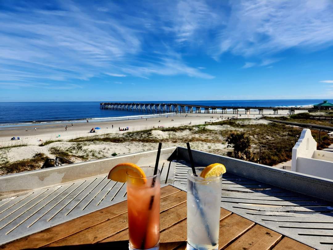 Two drinks sitting on a bar overlooking the Atlantic Ocean and a fishing pier. Penthouse Bar Things to do in Jax Beach Florida