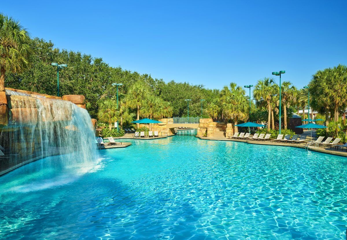 Walt Disney World Swan & Dolphin Resort Orlando Florida Family pools with large lagoon style pool. A large waterfall cascades from a rock and walking bridge leads to hidden places.