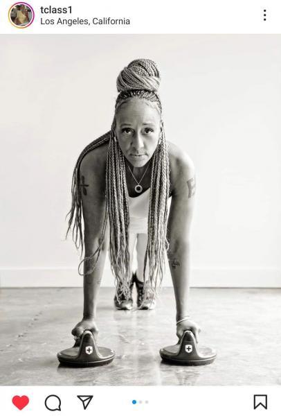 Toni, a remarkable fitness guru over 60, defying aging stereotypes. She's a strong, in-shape Black woman with long braided hair, depicted in a powerful plank position while holding weights. This black and white image sends a compelling message about the strength and vitality that age can bring.