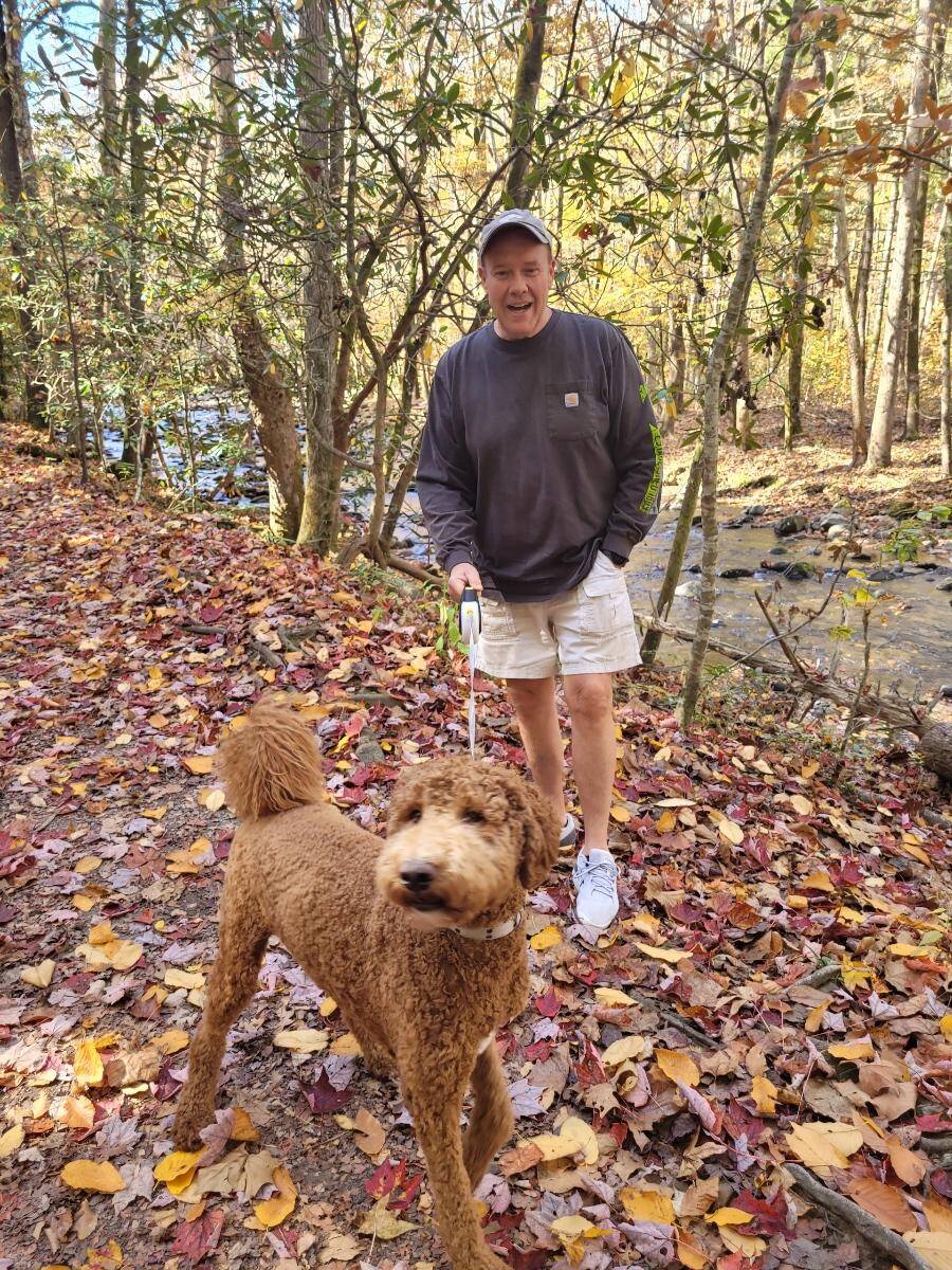 Steve and Mr. Jax an adorable goldendoodle walk a hiking trail in the mountains.