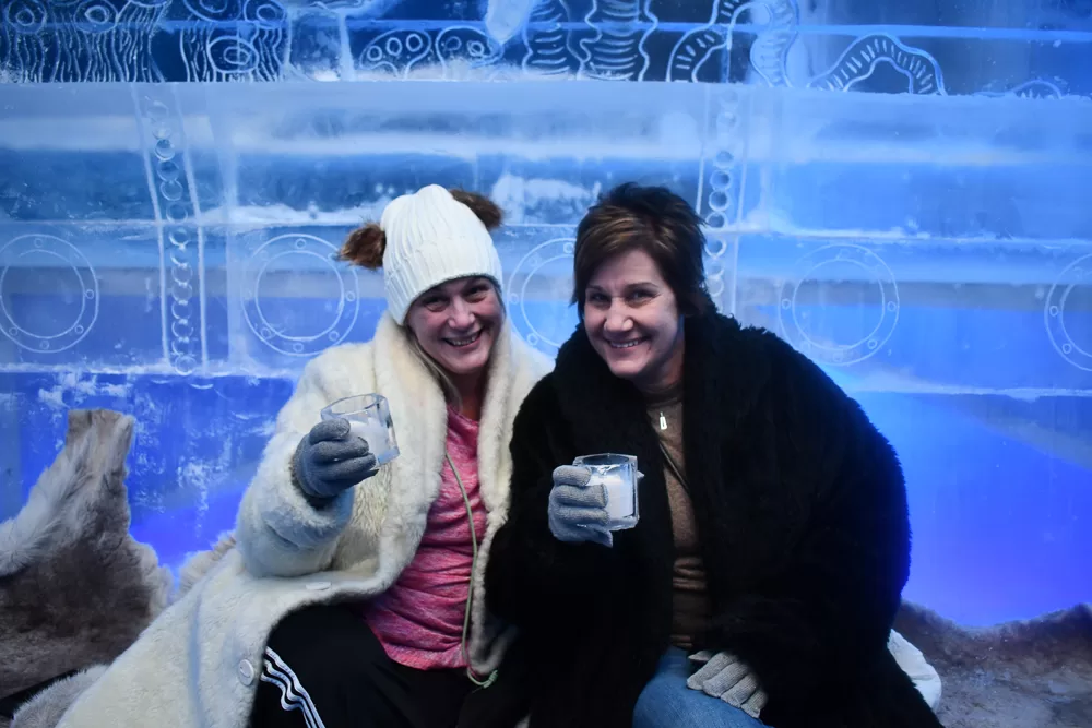Sisters Chris and Kathy bundle up in cozy faux fur parkas and winter hats, their gloved hands clutching frosty espresso drinks served in ice glasses. They grin in delight amidst the icy wonderland of the Minus5 ICEBAR Las Vegas, a frozen oasis in the midst of the desert heat.