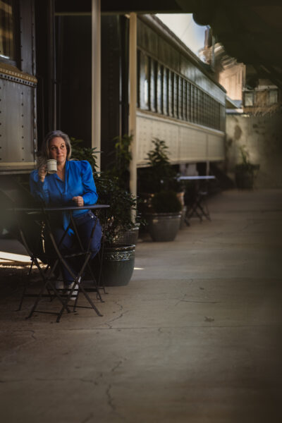 A woman sits amongst vintage railroad cars while sipping coffee. Chattanooga, Tennessee’s Kathy Brown is enjoying the peace while relaxing. Image Credit: CHRISTIAN MICHELLE PHOTOGRAPHY